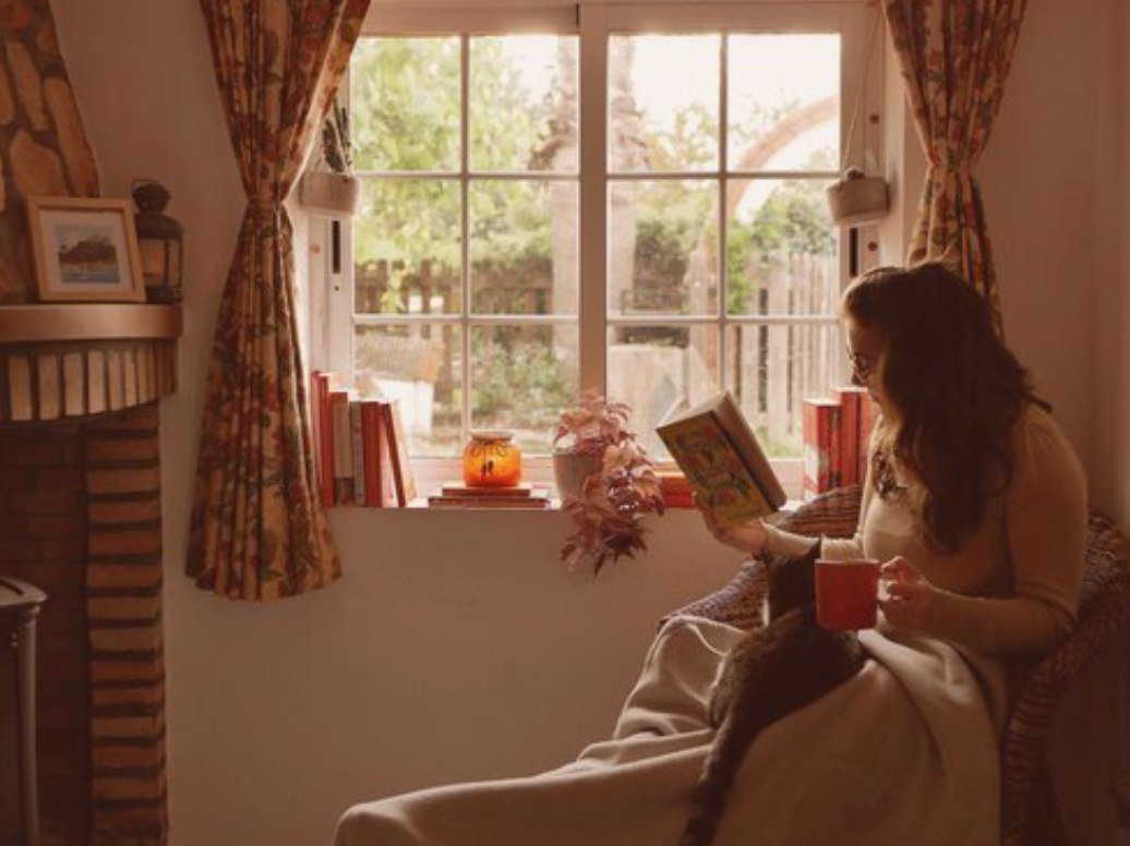 Online coach reading book with cat and tea